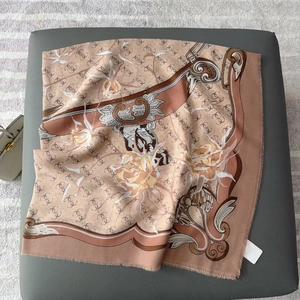 Close-up of pink square scarf featuring large floral prints and fine fringe detailing