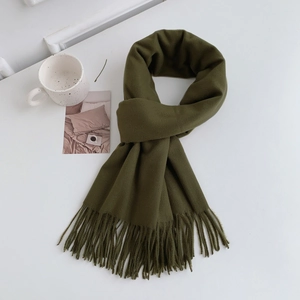 Close-up of dark green thick scarf with long fringe tassels on white desk