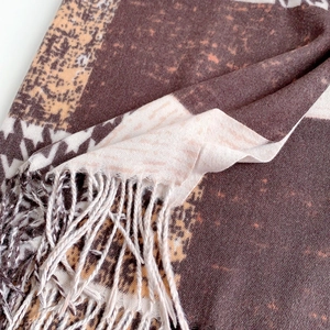 Detailed view of brown houndstooth pattern scarf with soft fringe and knit texture