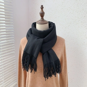 Detail of soft black cashmere-like scarf with dense fringe tassels on a mannequin