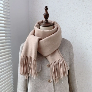 Detail of apricot cashmere-like winter scarf featuring thick knit fabric and long tassel trim