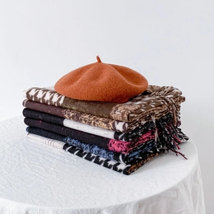 Houndstooth cashmere-feel scarves collection with an orange beret on a textured table