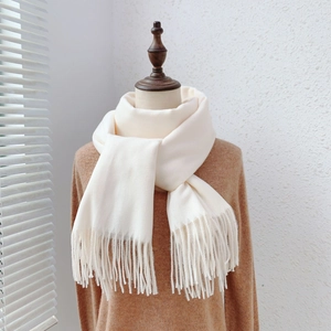 Close-up of off-white cashmere-like scarf texture with delicate fringe on mannequin