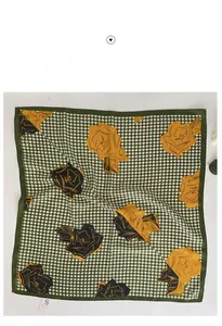 Dettaglio di un foulard in seta verde e bianco con motivo pied de poule e rose gialle
