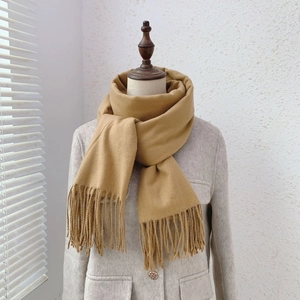 Detail of ginger yellow tassel scarf texture on light grey wool coat with natural lighting