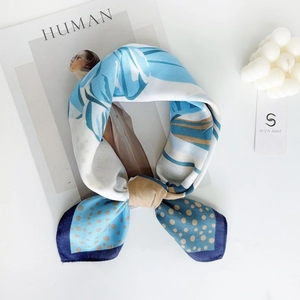 Close-up of elegant blue leaf print silk scarf with cream dots and dark blue borders