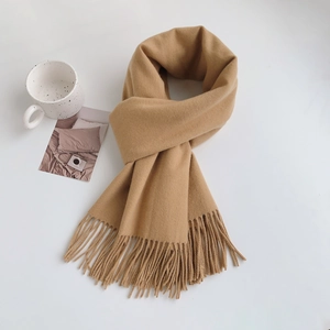 Close-up of soft camel cashmere-like scarf with elegant fringe detail on white background