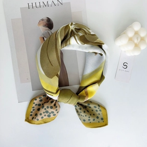 Detail of satin scarf with olive green and yellow floral patterns on white background