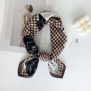 Dettaglio del foulard di seta marrone con motivo pied de poule e etichetta logo