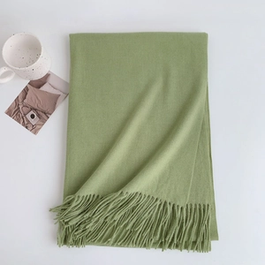 Detail shot of avocado green cashmere-feel scarf with delicate fringe on white background