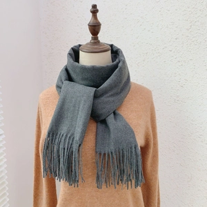 Detail of soft dark grey cashmere-like scarf featuring thick texture and long tassels