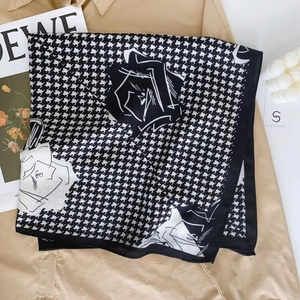 Dettaglio foulard pied de poule con motivi a rose posato su un trench coat beige