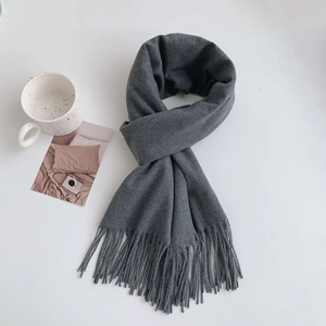 Detail view of dark grey winter scarf featuring long tassels and soft cashmere-like texture