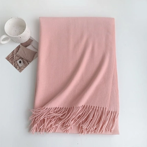 Detail of soft pink cashmere-feel winter scarf featuring delicate fringe edges and thick texture