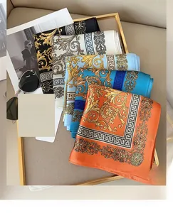 Détail de foulards en soie baroque avec motifs grecs et fioritures présentés sur un plateau