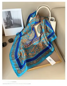 Détail d'un foulard en soie bleu avec motifs paisley dorés drapé sur un sac à main blanc