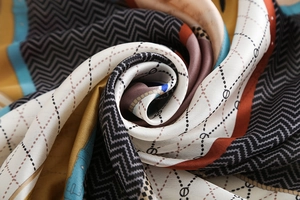 Detailed close-up of colorful geometric pattern scarf with silky satin texture and drape