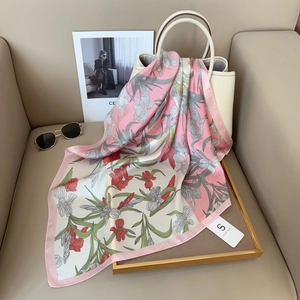 Detail of silk-feel scarf with floral iris print draped on a stylish beige handbag