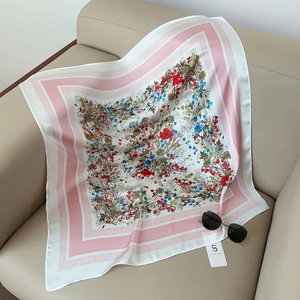 Vue détaillée d'un foulard carré en soie à imprimé floral sur un canapé en cuir beige