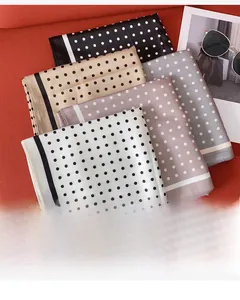 Dettaglio di cinque foulard in seta a pois con etichette su sfondo in tessuto rosso