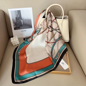 Elegant geometric square silk scarf with chain print draped over a luxury handbag