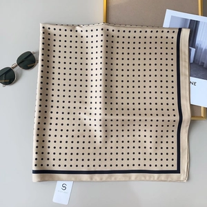 Dettaglio del foulard di seta champagne a pois con elegante bordo nero e finitura satinata