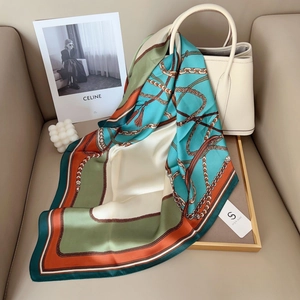 Elegant square silk scarf with chain tassel patterns draped over a white luxury handbag