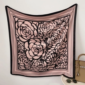 Detailed texture of silk square scarf featuring black camellia print on pink silk