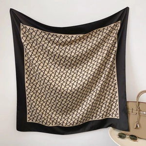 Detailed view of luxury twill silk scarf with letter monogram print and black borders