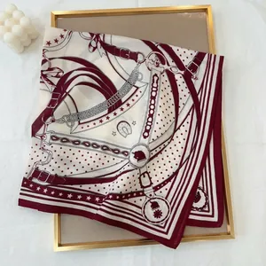 Detail of burgundy equestrian chain print scarf on a tray with decorative elements