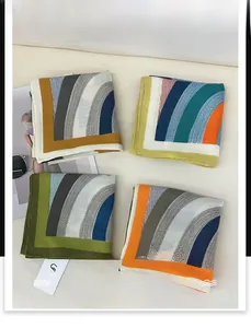 Detailed close-up of herringbone pattern silk scarves in four elegant colors with brand tag