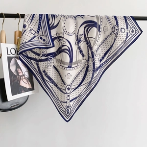 Detail of navy silk scarf with chain horse pattern draped near fashion magazine