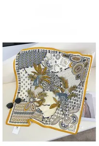 Detail of silk satin scarf featuring tropical palm and leopard print on a sofa