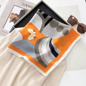 Detail view of orange silk scarf with geometric patterns and butterfly on knitwear