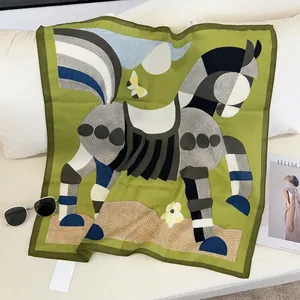 Close-up of artistic silk scarf with green horse pattern on a minimalist sofa