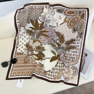 Detail of square silk scarf with leopard and tropical palm patterns on white sofa