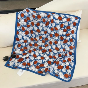 Close-up of blue tulip patterned silk scarf with broad borders and a brand tag