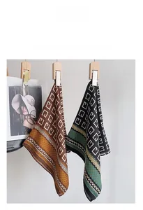 Detailed view of geometric herringbone silk scarves hanging on wooden clips with stylish texture