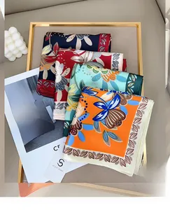 Detail of silk-like floral square scarves in navy, red, and blue with satin finish texture