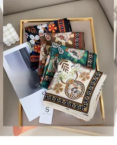 Detailaufnahme bedruckter quadratischer Tücher mit Blumenmustern auf einem Goldtablett