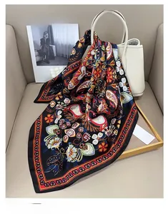 Detail eines bedruckten Seidenschals mit Paisley-Muster auf einer weißen Lederhandtasche