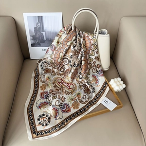 Eleganter Seidenschal mit Paisley-Muster drapiert über einer Lederhandtasche