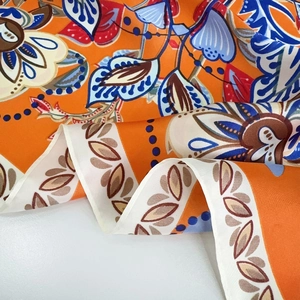 Detail of elegant orange floral silk scarf showing glossy texture and vintage pattern