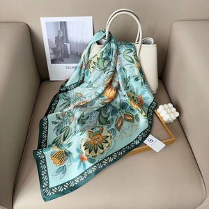 Light blue floral silk scarf with orange patterns draped over a white leather handbag