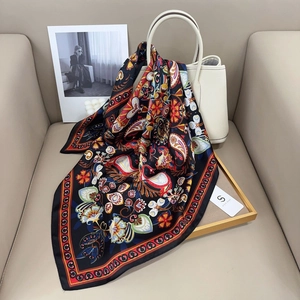 Detail eines Seidenschals mit Paisley-Muster in Schwarz und Rot auf weißer Tasche