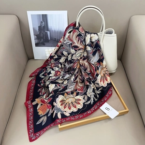Detail of silk-feel square scarf with floral print draped over a white handbag
