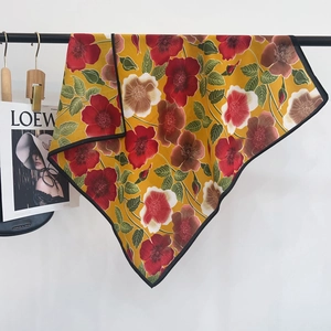 Close-up of yellow floral scarf with red blossoms and premium black hemmed edges