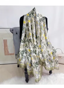 Detail of silk satin scarf featuring elegant daisy patterns draped on a velvet chair