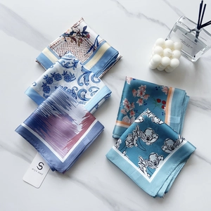 Flat lay of five floral silk scarves in various patterns on a marble background