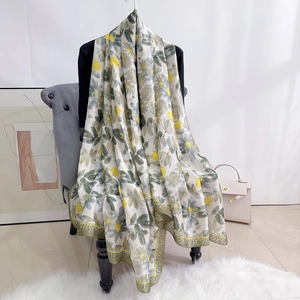 Detail of floral silk satin scarf featuring yellow flowers and olive green border on chair